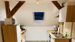 Una cocina compacta con muebles de madera, un microondas integrado y una ventana sobre el fregadero.