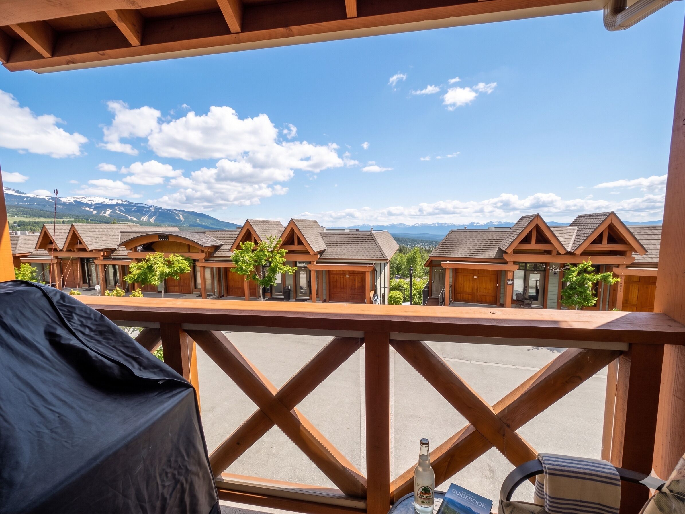 Un balcon offrant une vue sur des chalets en bois et, au loin, sur des montagnes.