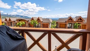 A balcony with a view of wooden cabins and mountains in the background.