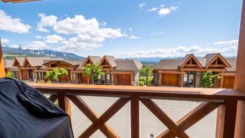Un balcon offrant une vue sur des chalets en bois et, au loin, sur des montagnes.