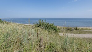 Kustlandschap met heldere lucht, een begroeiing van gras en uitzicht op de zee.