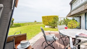 Een terras met een tafel, stoelen, een kop koffie en uitzicht op zee.