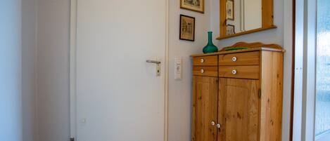 A room with a wooden wardrobe, a door, and a wall-mounted mirror.