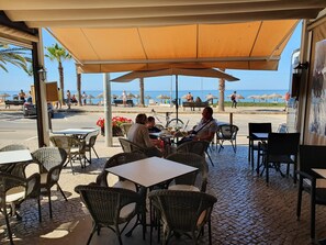 Enjoy a meal with a view of the beach from our outdoor seating area, surrounded by palm trees and cobblestone paving.
