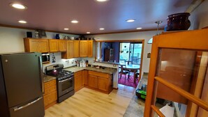 A kitchen with wooden cabinets, a refrigerator, a stove, and a microwave. - Hillside Haven (Penn Yan)