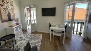 A living room with a sofa, a coffee table, a TV, and a dining area with chairs and a table. - Charming one-bedroom apartment in the heart of the city (Guimarães)