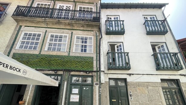 A building with a green awning labeled "PER BOCK" and a sign "Super Bock". There are outdoor tables and chairs in front of the entrance. - Charming one-bedroom apartment in the heart of the city (Guimarães)