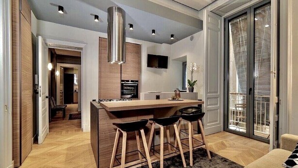 A modern kitchen with a central island, bar stools, and a dining area. - Luxury apartment in the historic center (Catania)