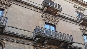 A building with ornate balconies and a large arched entrance. - Luxury apartment in the historic center (Catania)