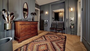 A hallway with a wooden dresser, a patterned rug, and a mirror. - Luxury apartment in the historic center (Catania)