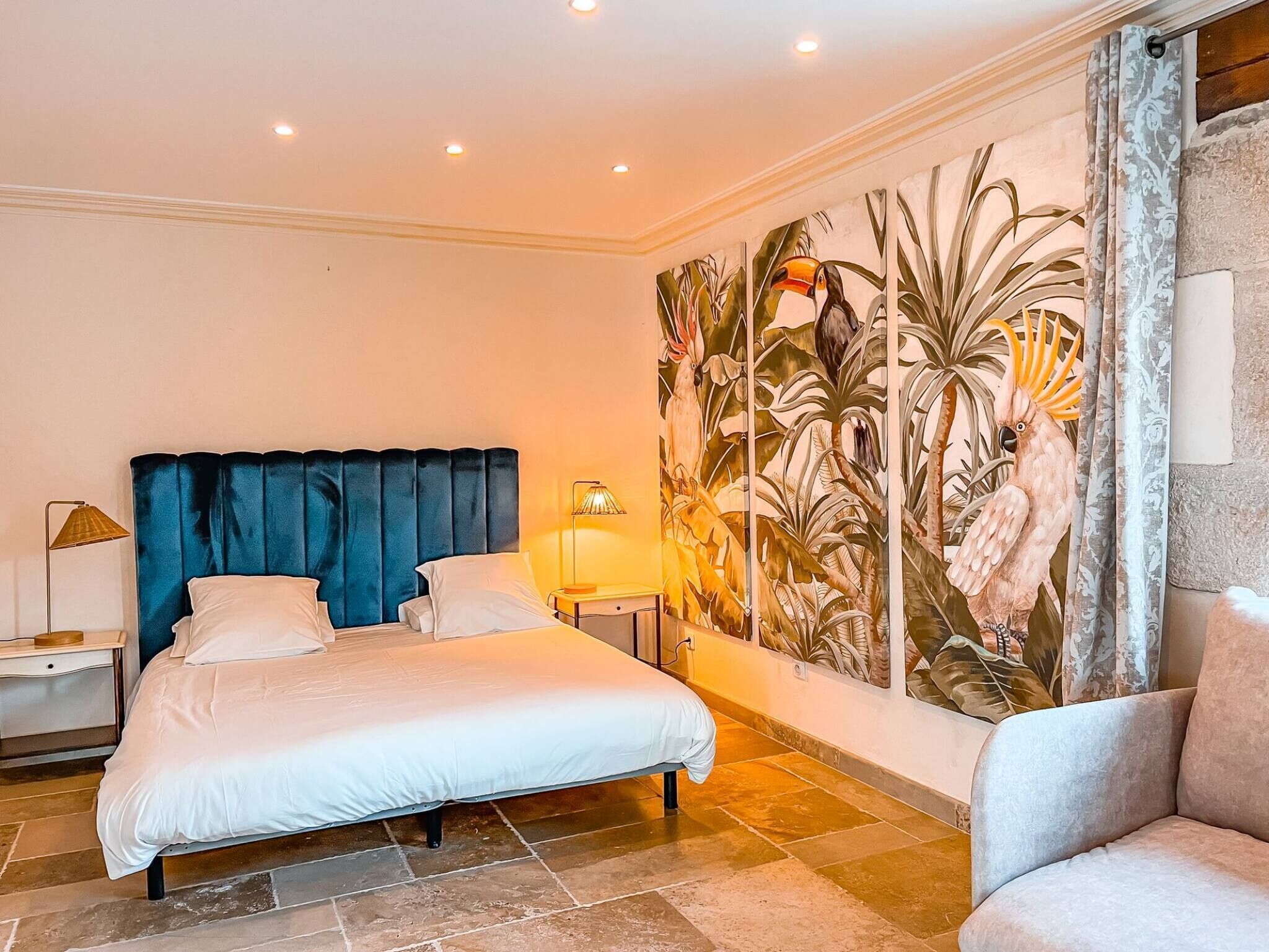 Una camera da letto con un letto grande, un comodino, una lampada e un affresco sulla parete.