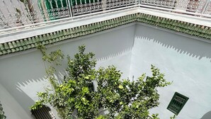 A courtyard with a tiled floor, green plants, and a white wall with decorative metal railings. - Riad Dar Bibas - just a 10-minute walk from Jema el Fna square (Marrakech)