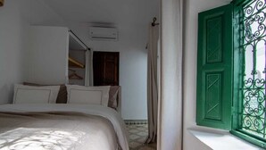 A bedroom with a bed, a wardrobe, and a window with green shutters. - Riad Dar Bibas - just a 10-minute walk from Jema el Fna square (Marrakech)