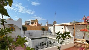 A rooftop terrace with a white railing, potted plants, and a clear blue sky. - Riad Dar Bibas - just a 10-minute walk from Jema el Fna square (Marrakech)