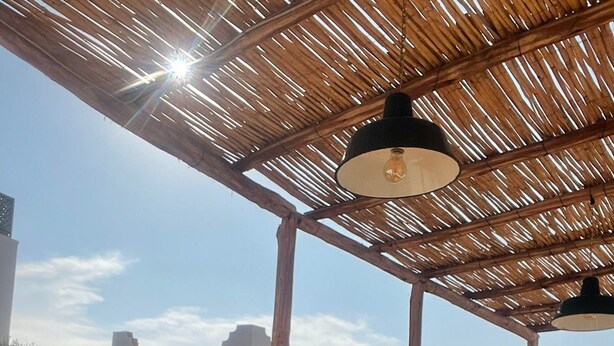 An outdoor patio with a wooden table and chairs, a white railing, and a building with a white facade in the background. - Riad Dar Bibas - just a 10-minute walk from Jema el Fna square (Marrakech)