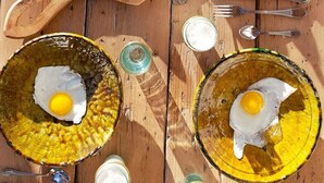 A wooden table with breakfast items including pancakes, pomegranate halves, and fried eggs on a sunny day. - Riad Dar Bibas - just a 10-minute walk from Jema el Fna square (Marrakech)