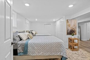 A bedroom with two beds, white walls, and a wooden floor. - Sweet & Cozy Studio Apartment (South Burlington)