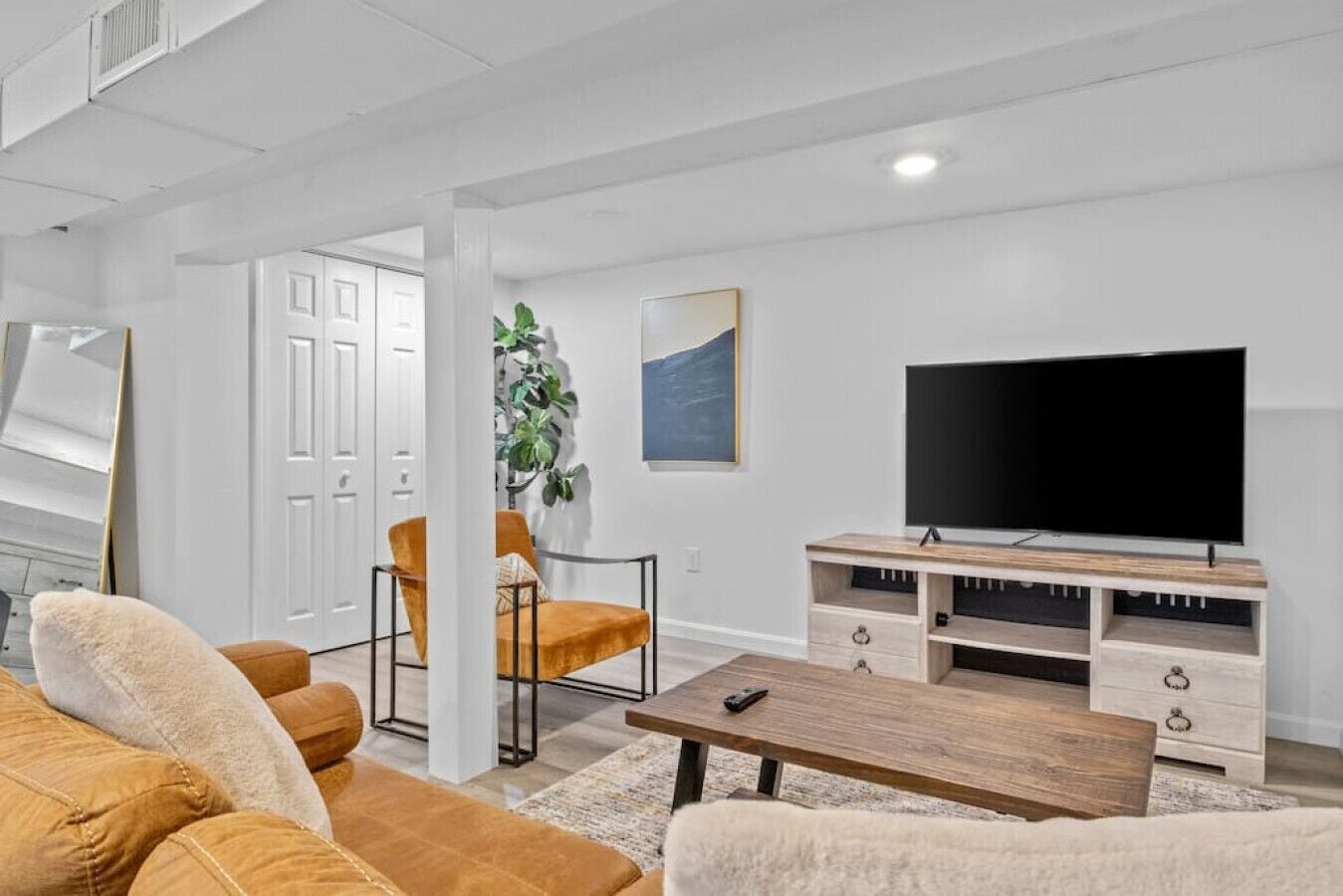 A modern living room with a large flat-screen TV, a wooden coffee table, and two armchairs.