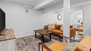 A modern living room with a sofa, coffee table, and a TV stand.