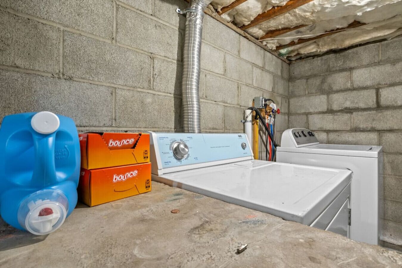 Un espace buanderie comprenant un lave-linge, un sèche-linge et des boîtes de lessive empilées.