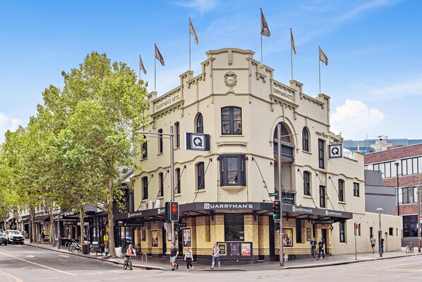 A historic building with multiple flags, a prominent sign for 'Quarryman's Hotel', and a street-level entrance with a covered area.