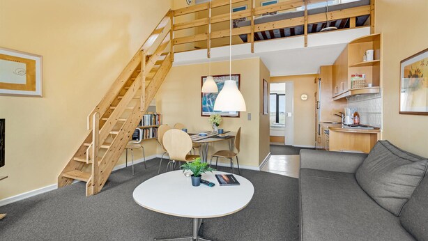 Ein modernes Wohnzimmer mit Treppe, Essbereich und Küche.