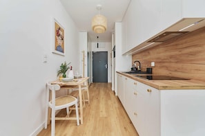 Une cuisine étroite avec des meubles blancs, un plan de travail en bois et un luminaire suspendu.