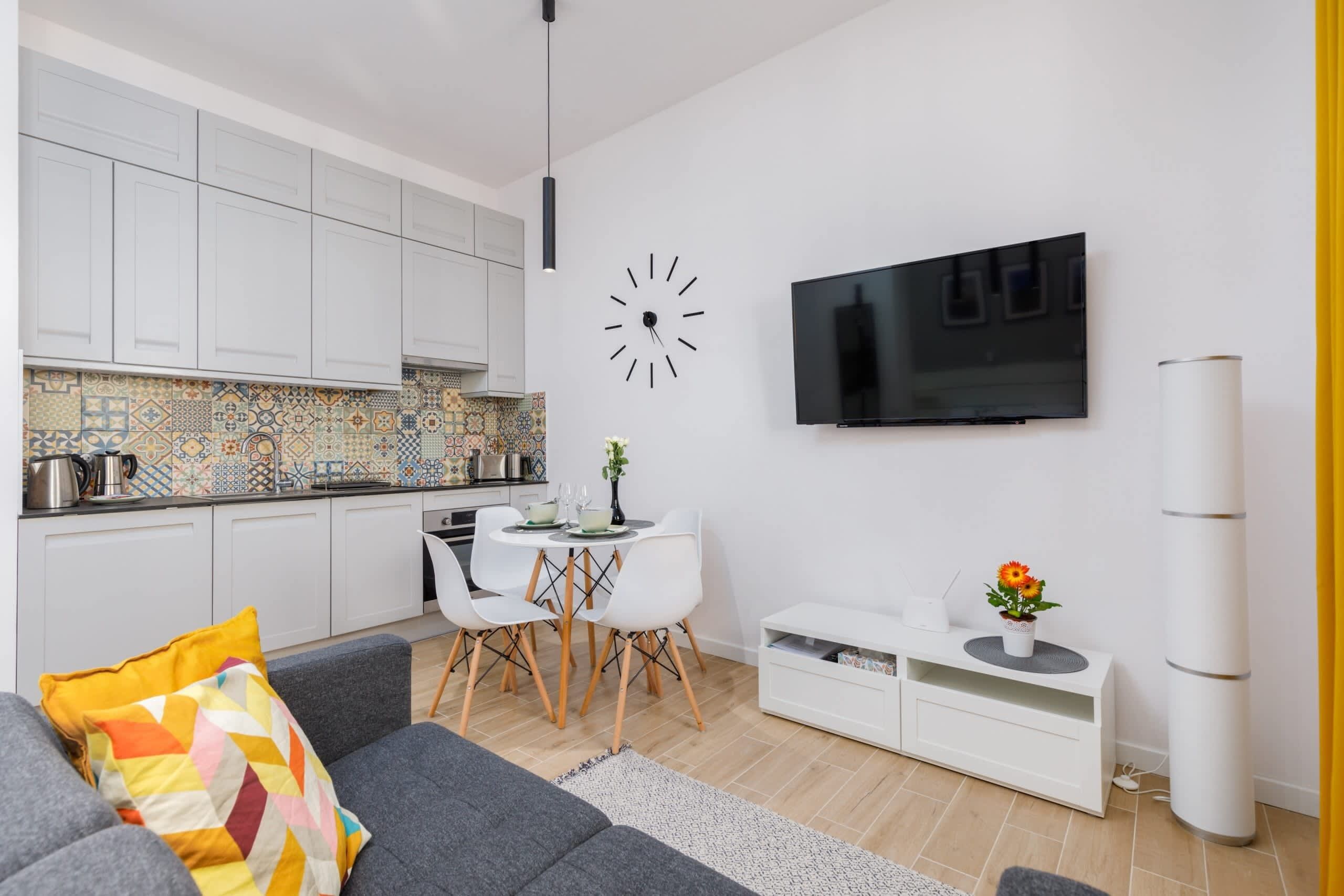 A modern living space with a kitchen, dining area, and a TV mounted on the wall.