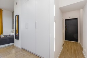 Een moderne hotelkamer met een bed, een kledingkast en een deur die naar een andere kamer leidt.