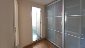 A hallway with a sliding glass door leading to a tiled area, a wooden floor, and a large sliding glass closet.