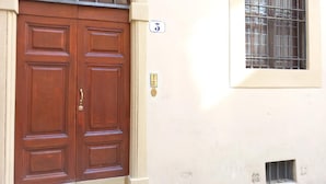 A double wooden door with a brass handle, a number '3' sign above it, and a barred window to the right.