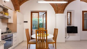 A modern kitchen with a dining area, featuring a brick ceiling, white walls, and a large window. - San Zanobi 33 in Firenze (Florence)