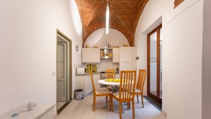 A compact kitchen with white cabinets, a round table, and wooden chairs. - San Zanobi 33 in Firenze (Florence)