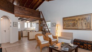 Un'ampia zona giorno con soffitto alto, una cucina sullo sfondo, mobili in vimini e un grande dipinto a tema egizio.