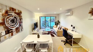 A modern living room with a dining area, a sofa, a TV, and a large abstract painting on the wall. - Beige & Beautiful - Close to ANU (Turner)