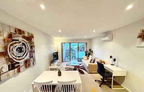 A modern living room with a dining area, a sofa, a TV, and a large abstract painting on the wall. - Beige & Beautiful - Close to ANU (Turner)