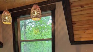 Ein Schlafzimmer mit großem Fenster, einem Holz-Kopfteil, einem Bett mit weißer Bettwäsche, zwei Nachttischlampen und einem Nachttisch mit Lampe.