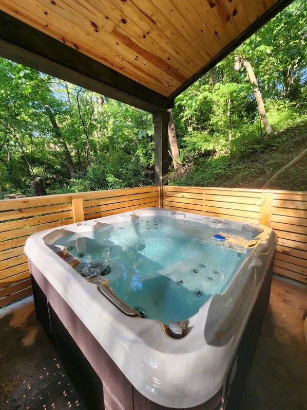 A hot tub in a wooden structure with a natural forest view.