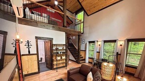 Ein großzügiger Loft-Wohnbereich mit braunem Ledersofa, einem Couchtisch und einer Treppe, die in eine obere Ebene führt.