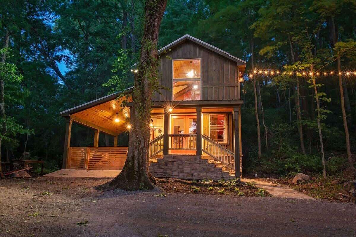 A cabin with a covered porch, a staircase, and a string of lights.