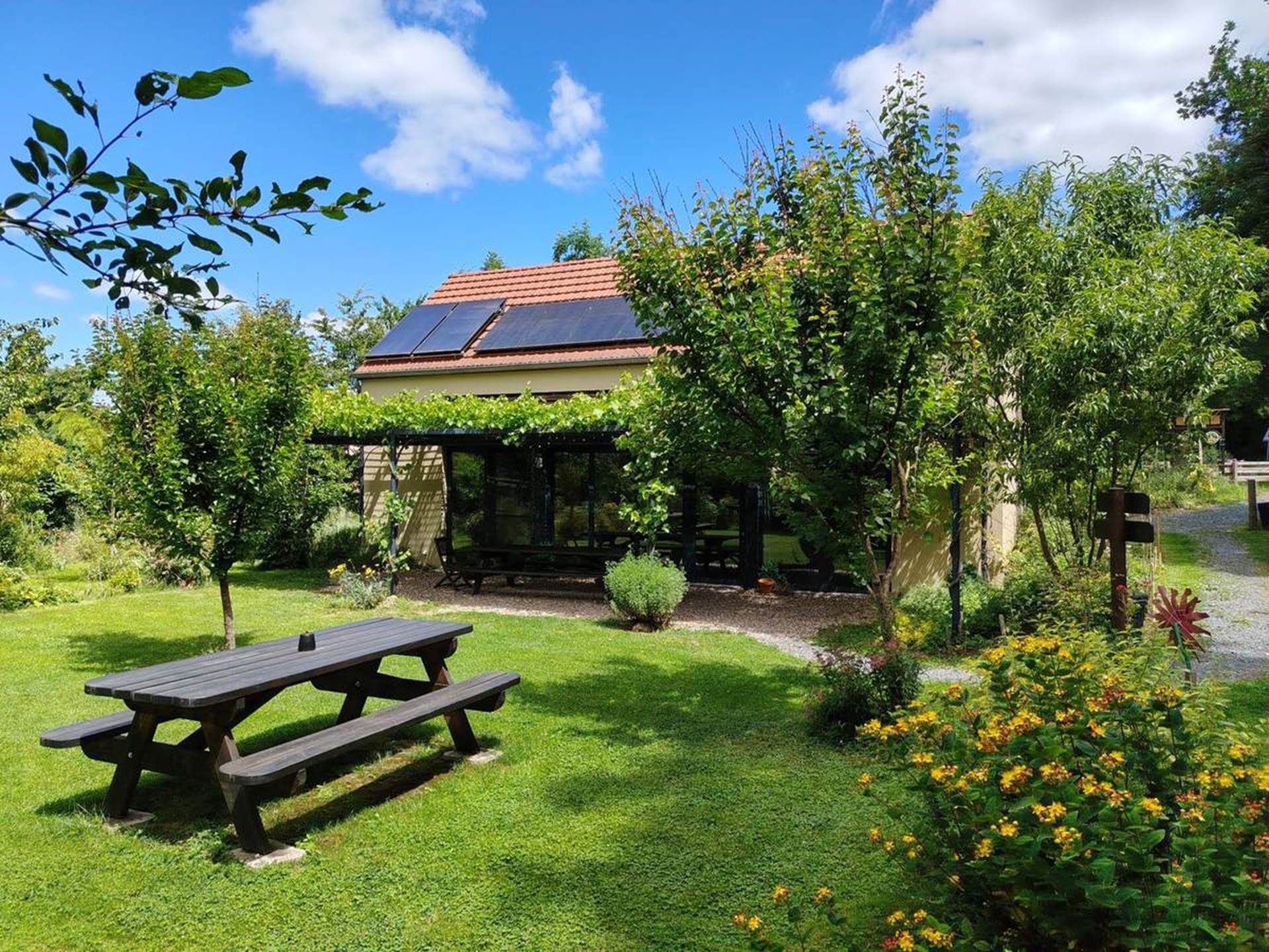 A house with a garden, a picnic table, and solar panels on the roof.