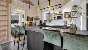 Una cucina moderna con angolo bar, caratterizzata da una grande isola, sgabelli da bar, illuminazione a sospensione e vista sull'esterno.
