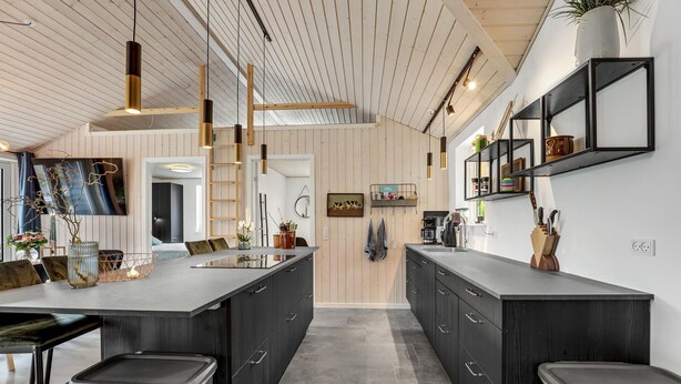 Una cucina moderna con isola centrale, mobili scuri e soffitto in legno.