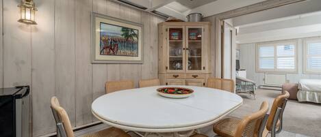 A dining area with a round table, six chairs, a cabinet with glass doors, and a ceiling fan.