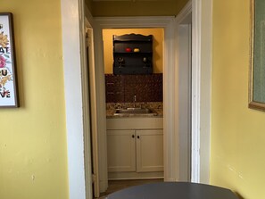 Enter a cozy space with a compact kitchen featuring a sink, countertop, and backsplash with a patterned tile design.
