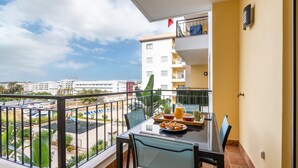 En balkon med et bord dækket til morgenmad, udsigt over byen og et flag på bygningen.