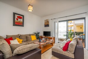 Un salon comprenant un canapé, une table basse, un téléviseur à écran plat et un balcon avec vue.