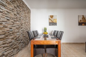 Une salle de conférence avec une table en bois, des chaises noires, un panier de fruits et des œuvres d’art abstraites accrochées au mur.