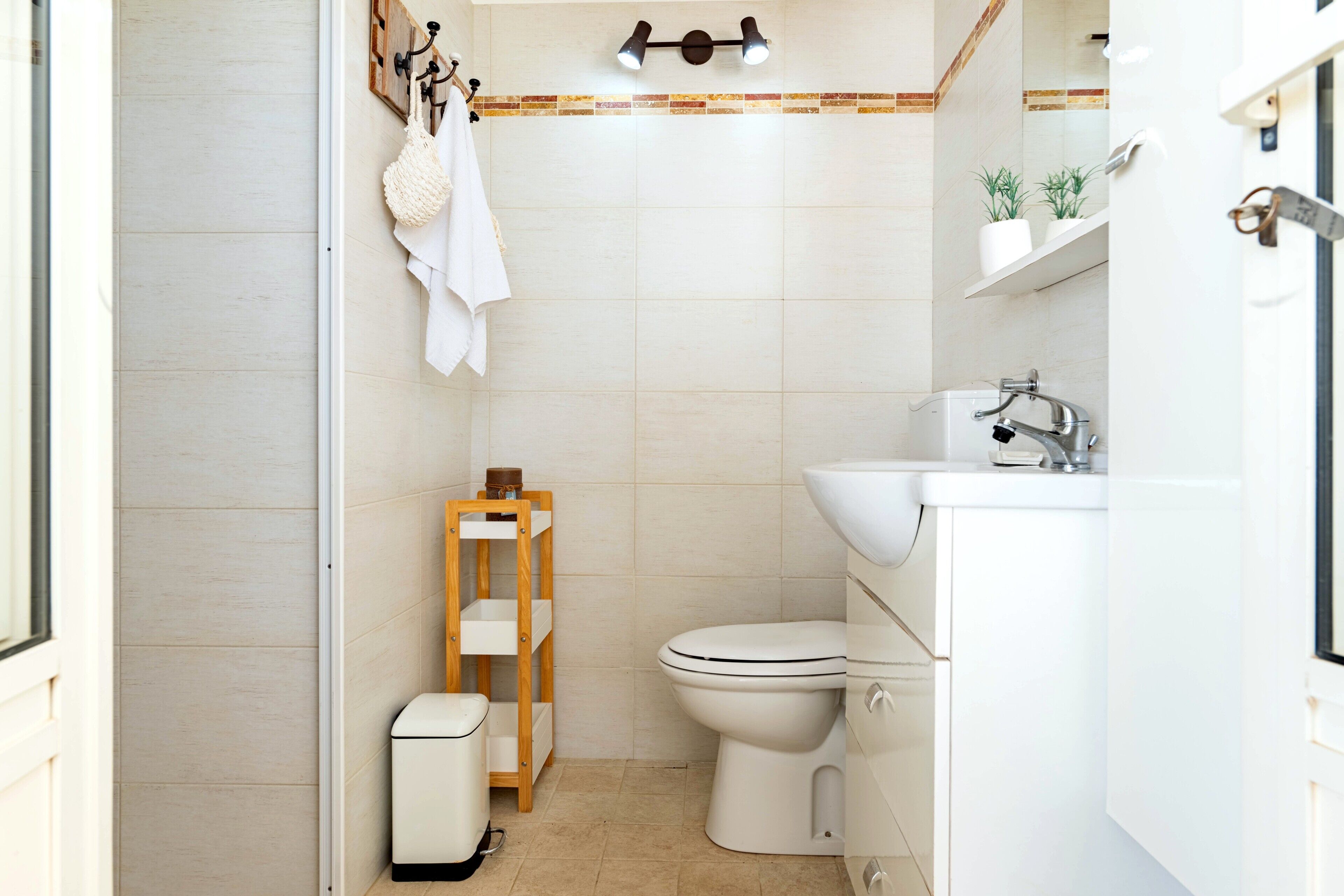 A compact bathroom with a toilet, sink, and storage shelves.
