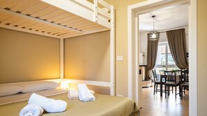 Ein Zimmer mit Etagenbett, einem Essbereich mit Stühlen und einem Tisch.